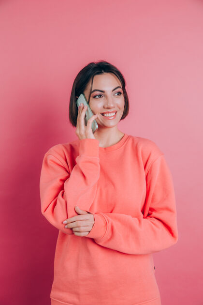 脸这张照片是一位女士在粉色背景下用智能手机聊天时微笑的照片情绪微笑休闲