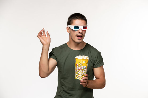 帅哥正面图身穿绿色t恤的年轻男性手持爆米花戴着d墨镜在白色办公桌上拍摄电影孤独电影院男性电影成人电影院男人