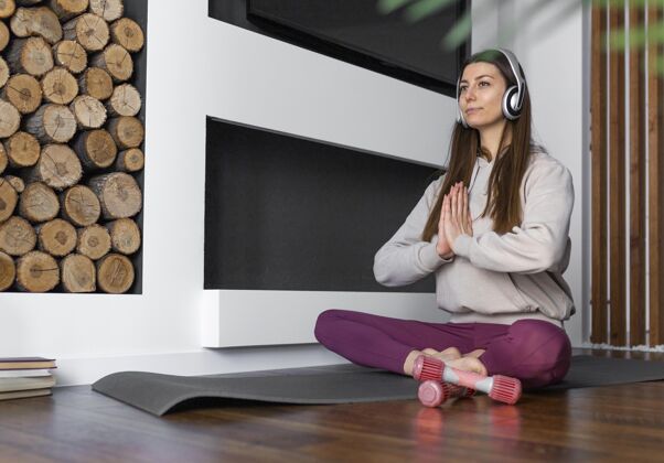 哑铃坐在瑜伽垫上的全镜头女人生活室内耳机