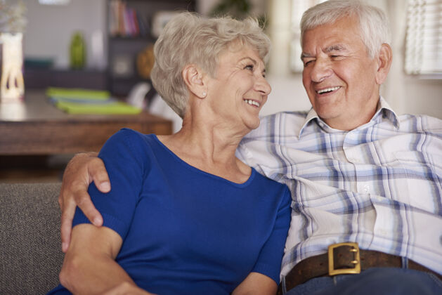拥抱快乐的老年夫妇坐在沙发上男人拥抱家居内饰