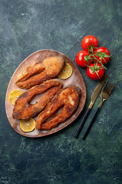 食物俯瞰图炸鱼和柠檬片在一个棕色的盘子西红柿餐具设置在混合颜色表与自由空间调料晚餐椒盐卷饼