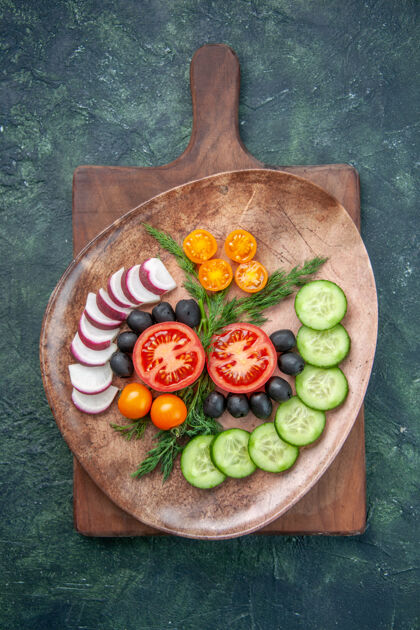 饭上图：棕色盘子里的新鲜切碎蔬菜放在五颜六色的木质砧板上盘子胡椒西红柿