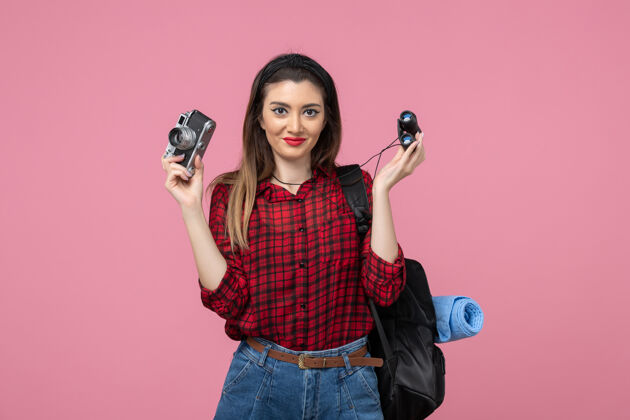 漂亮前视图年轻女性用望远镜和相机在粉色背景上拍摄人色女人头发脸年轻女性