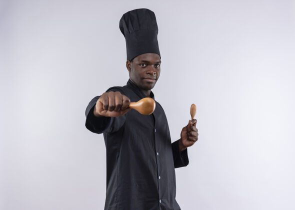空间年轻自信的美国黑人厨师身着厨师制服 站在一旁 拿着白色的木勺子 留有复印空间厨师举行烹饪