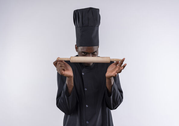 厨师年轻的美籍黑人厨师身着厨师制服 拿着擀面杖看着白色的擀面杖 留着复印空间请别针卷