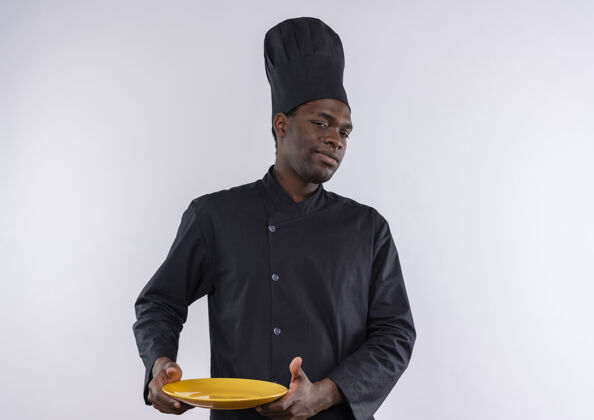 盘子年轻自信的美国黑人厨师穿着厨师制服 拿着盘子 看着白色的相机 留着复印空间制服厨师自信