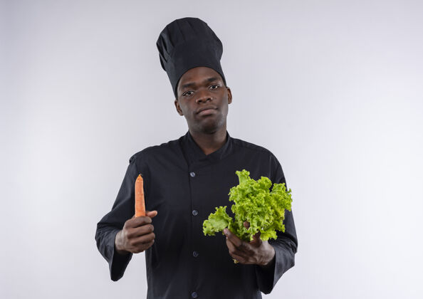 非裔美国人年轻自信的美国黑人厨师身着厨师制服 拿着色拉和胡萝卜放在白底 留有复印空间烹饪制服空间