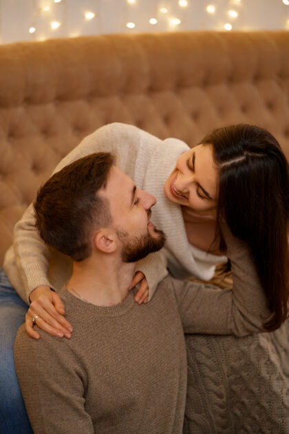 男人幸福的已婚年轻夫妇拥抱在一起 坐在舒适的沙发上在一起浪漫毛衣