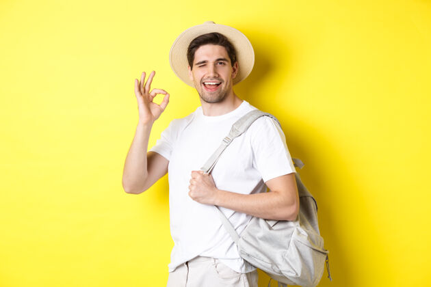 工作室旅游 旅游 度假理念快乐的旅游者去度假 背着背包 露出满意的微笑 站在黄色的背景下站着男人年轻人