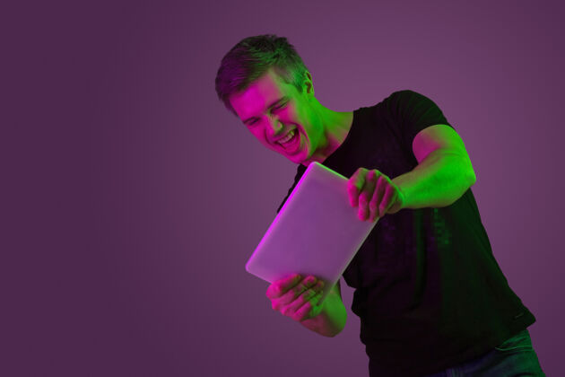 成功年轻人用霓虹灯玩平板电脑的画像快乐情感人