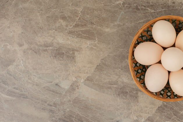 胆固醇大理石桌上放着一篮子白鸡蛋背景木头贝壳