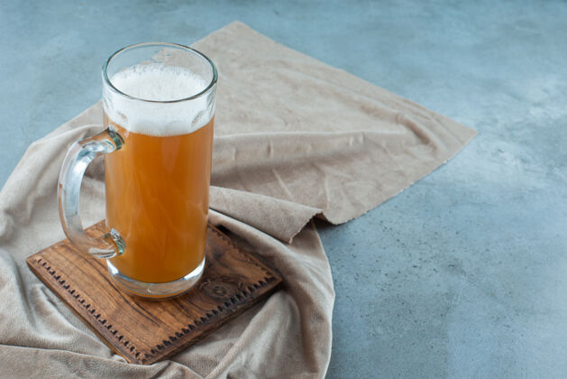 新鲜一杯啤酒放在毛巾板上 蓝色背景上美味啤酒美味