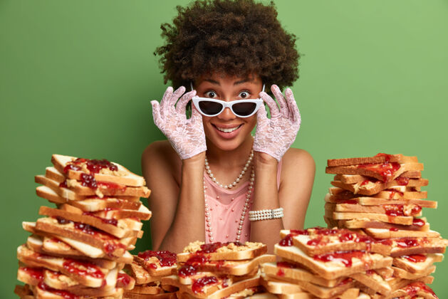 三明治迷人的女人 有着非洲头发 周围是花生酱果冻三明治年轻衣服肖像