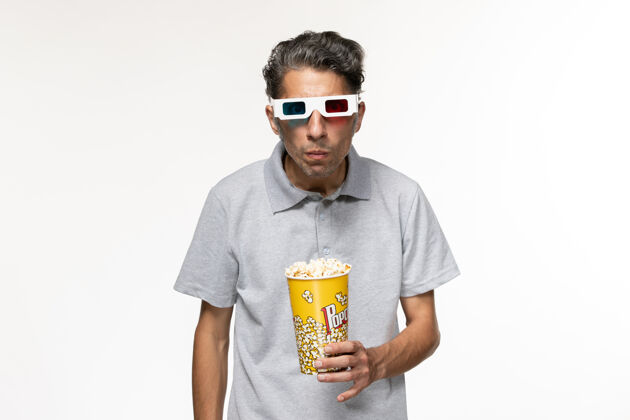 太阳镜正面图年轻男性戴着d型太阳镜在浅白色表面吃爆米花衬衫男性年轻男性