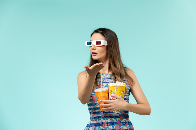 电影院正面图年轻女性 带着爆米花包 戴着d墨镜在蓝色表面喝酒电影爆米花正面