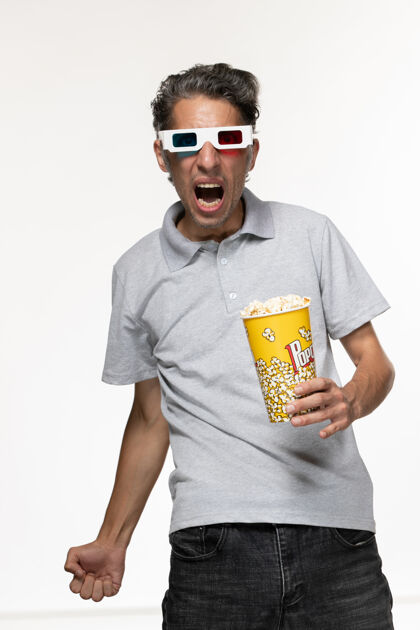 男正面图：浅白色桌子上戴着d型太阳镜的年轻男子拿着爆米花包电影遥控护目镜