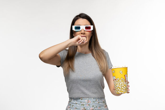 遥远正面图年轻女性手持爆米花 戴着d墨镜在白色表面看电影女性爆米花太阳镜