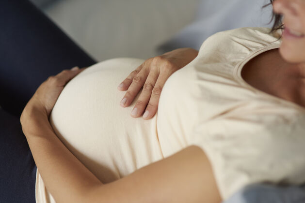 床单孕妇腹部的高角度视图怀孕人类腹部期望