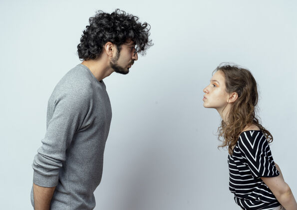女人一对年轻夫妇面对面站着 要在白墙上亲吻对方男人年轻脸