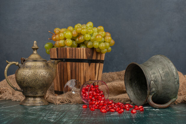 花瓶石榴籽和一桶葡萄放在大理石桌上 还有花瓶和茶壶经典种子有机