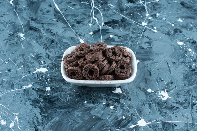 糖美味的巧克力涂层玉米圈在一个碗里 在大理石背景上美味牙套巧克力