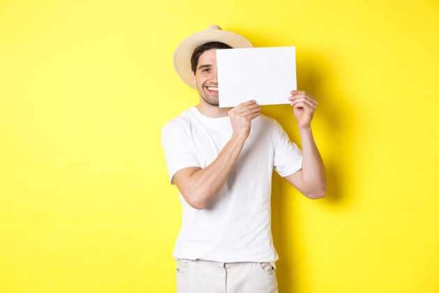 游客度假快乐的家伙 拿着一张空白的纸贴着你的标志 面带微笑 站在黄色的背景下表情男人成人