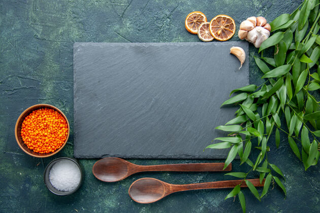 勺子顶视图橙色小扁豆配大蒜和盐 背景为深蓝色照片食物辛辣辣椒色尖利的种子汤木勺尖的器皿