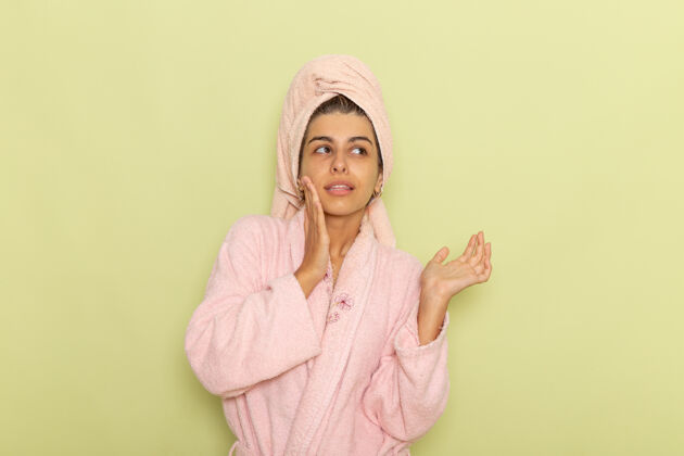 长袍正面图穿着粉红色浴袍的年轻女性在绿色表面上摆姿势前面衣服姿势