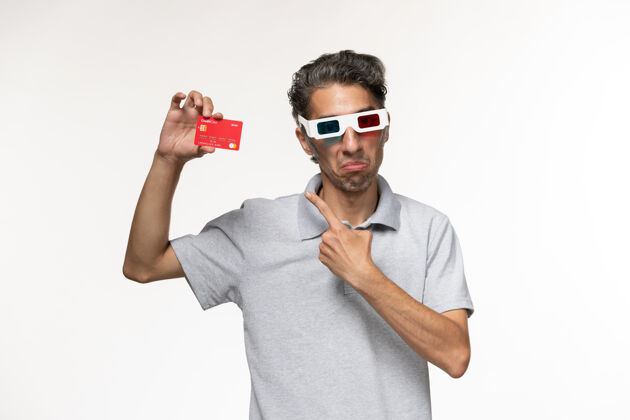 银行正面图年轻男子手持红色银行卡戴着d墨镜在白色表面年轻男性电影护目镜