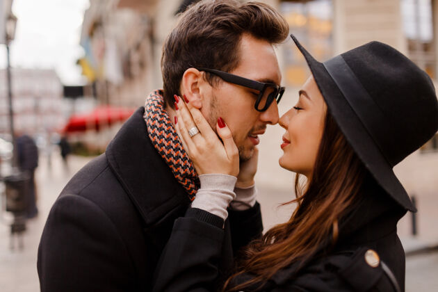 城市浪漫的情侣面对面的拥抱和微笑温暖舒适的色彩 冬天的心情帅哥和优雅的黑发女人漫步在城市里男性肖像街道