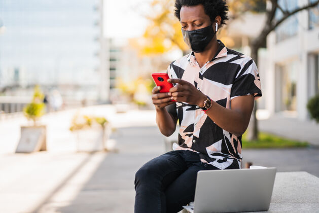 通讯一幅非洲男人在街上户外散步时使用手机的照片新的正常生活方式概念成人享受旅行