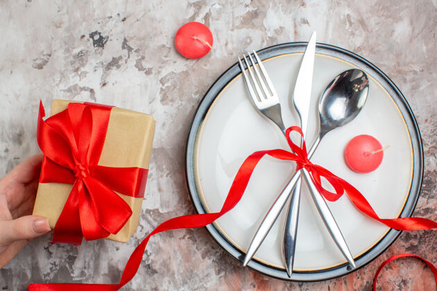 激情顶视图银色餐具勺子叉和刀与红色弓 并提出了一个光明的表面弓匙礼物