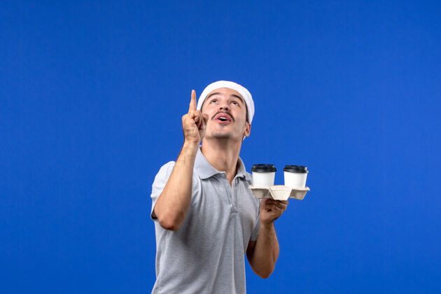 男人正面图年轻男子拿着咖啡杯在蓝色的墙上情感咖啡蓝色的人类成人杯子专业