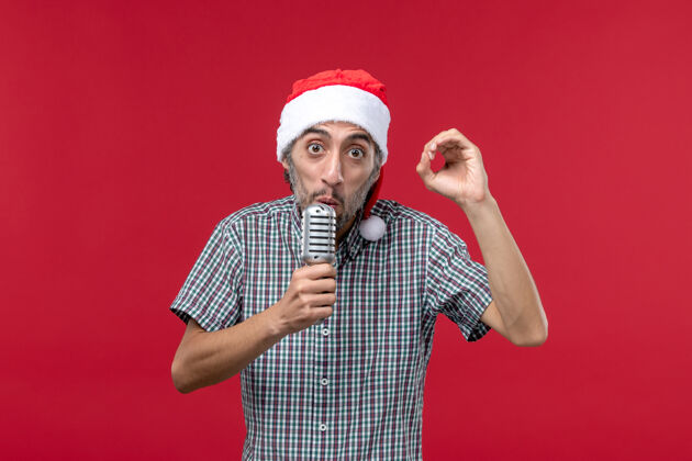 肖像正面图年轻人拿着麦克风在红墙情感节日歌手音乐圣诞节男性男人