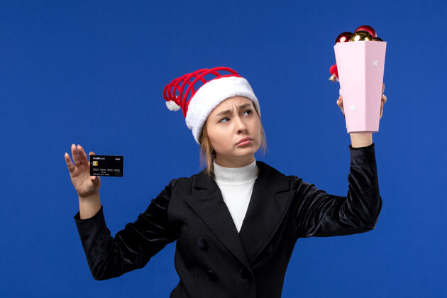 成人正面图年轻女士拿着银行卡在蓝色墙壁玩具新年情感假期圣诞节商人人