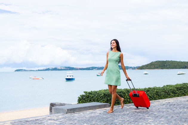 度假快乐的白种人漂亮的长发优雅的旅游女人在酒店外面穿着红色的手提箱女人散步积极