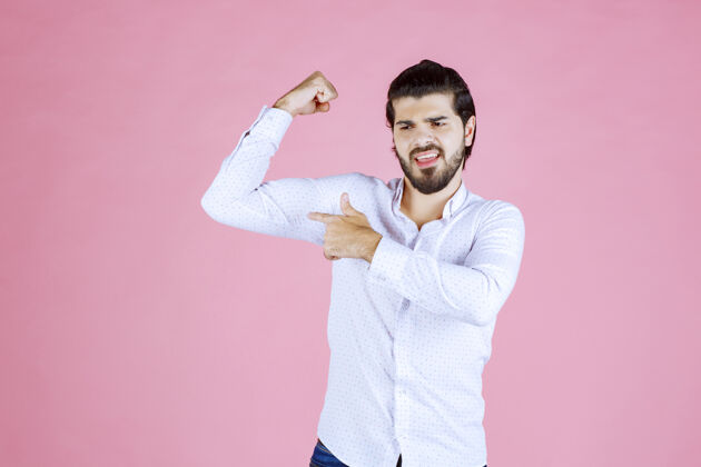休闲一个穿白衬衫的男人在展示他的手臂肌肉阳刚年轻人模特
