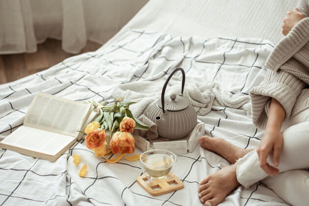 书女人在床上休息 茶 一本书和一束郁金香舒适花休息一天