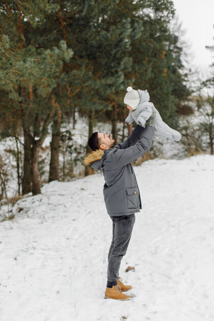 寒冷在一个阳光明媚的日子里 一家人在雪中散步 在冬季公园里玩得开心 互相拥抱 面带微笑欢乐关系玩耍