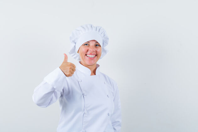 优雅穿着白色制服的女厨师竖起大拇指 看上去很快乐肖像显示时尚