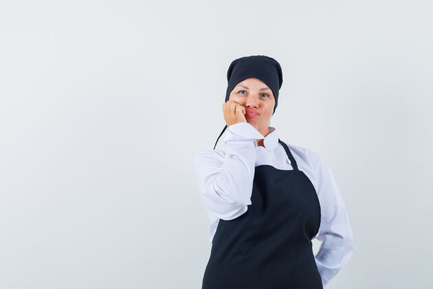 自然一个穿着黑色厨师制服的金发女人把脸靠在手上 想着什么 看起来很漂亮人黑色年轻