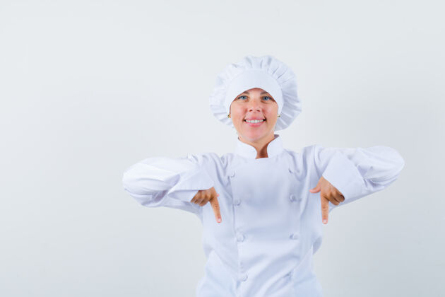 自信穿着白色制服的女厨师指着下面 看上去很自信表情欢呼时尚