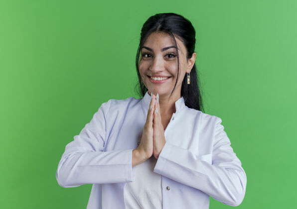 一起面带微笑的年轻女医生穿着医用长袍 双手紧握在绿色的墙上保持医学手