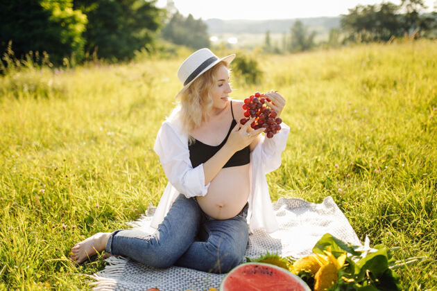 快乐年轻孕妇在公园户外放松 吃西瓜 健康怀孕阳光怀孕草地
