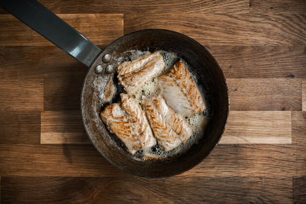 木头木桌上烤肉锅的顶视图烹饪鱼晚餐