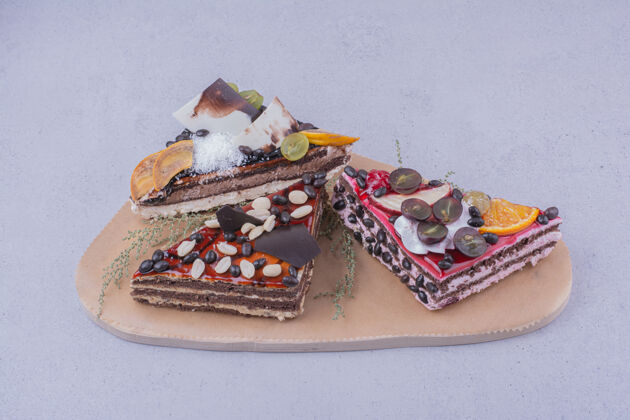 厨房三角形状的巧克力蛋糕片与坚果和水果放在一个木盘上健康美味面粉
