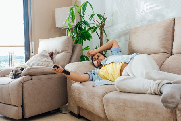 白种人一位英俊的西班牙裔男子躺在沙发上看电视的照片男人看年轻