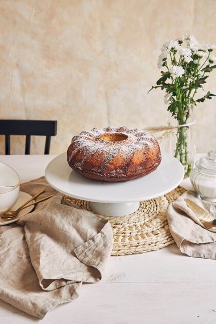 面粉美丽的镜头美味的环蛋糕放在一个白色的盘子和一个白色的花靠近它形状美味戒指