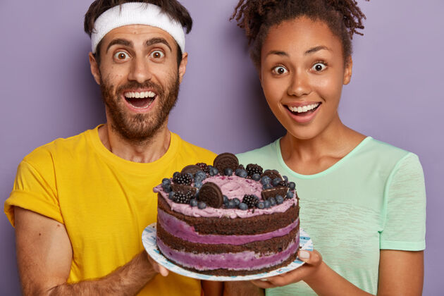 食物惊喜开朗的女人和男人把大蛋糕端上盘子 祝贺朋友生日糖零食一起
