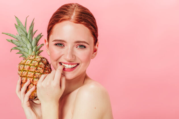红发性感的欧洲女人拿着菠萝的正面照片摄影棚拍摄的快乐女孩拿着水果对着镜头大笑女孩裸体女士